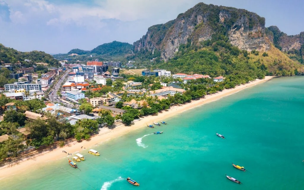 Longtail boats on Ao Nang beach with limestone cliffs in background